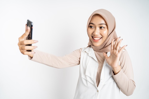 Femme en hijab tenant un téléphone intelligent pour selfie