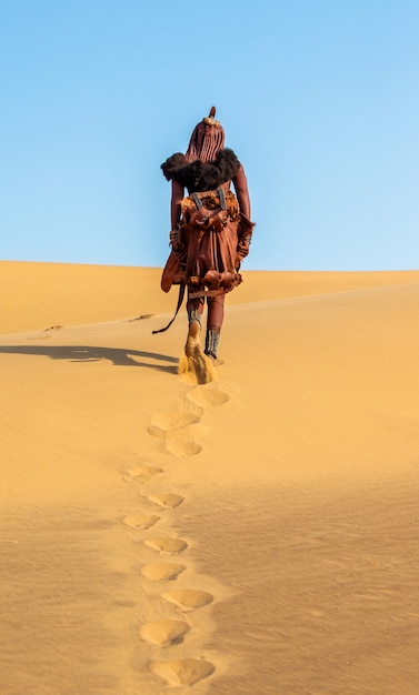 Une femme Himba en costume traditionnel se promène dans le désert.