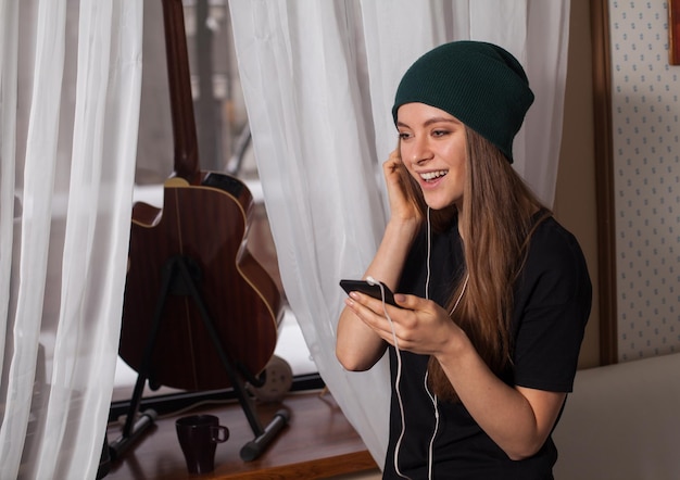 Femme hipster au chapeau vert écoutant de la musique et profitant de la vie