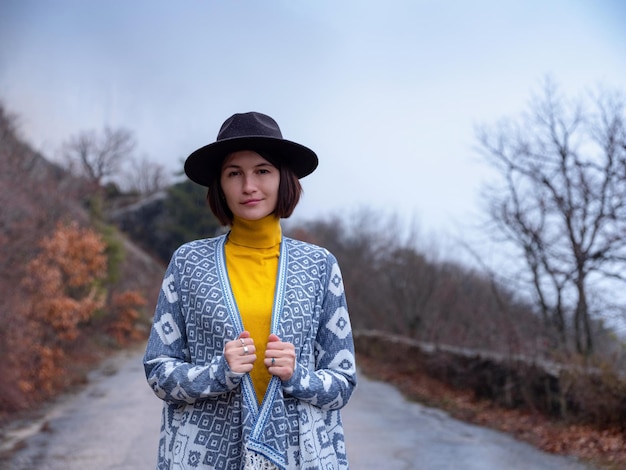 Femme hipster élégante dans un chapeau marchant sur une route de montagne