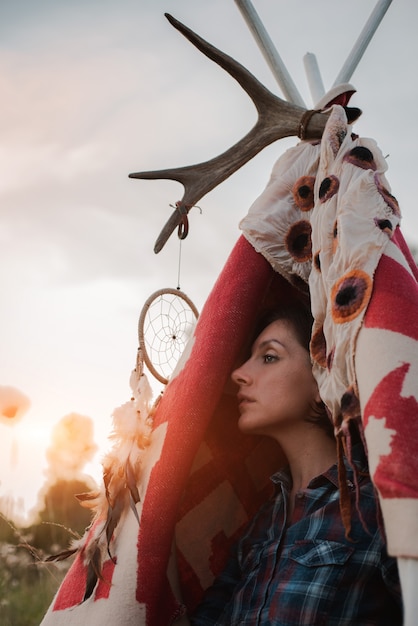 Une femme hipster en forme de chaman recherche l'inspiration de la Terre mère dans un wigwam dans la nature.