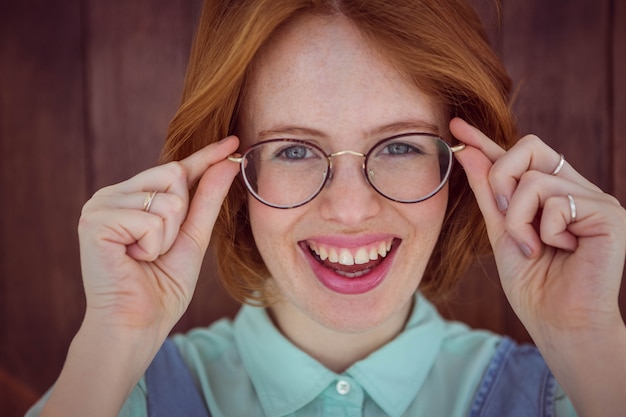 Femme hipster rousse tenant ses lunettes