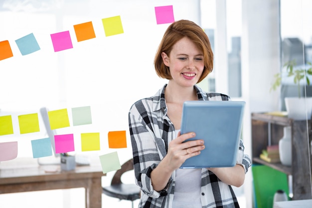 femme hipster souriante, assise à son bureau sur son taableet