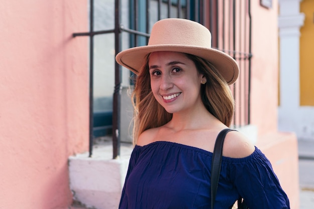 Femme hispanique avec un chapeau sur la tête en se tenant debout dans la rue