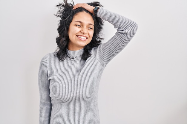 femme hispanique, à, cheveux foncés, debout, sur, arrière-plan isolé, sourire, confiant, toucher, cheveux, à, main haut, geste, poser, attrayant, et, à la mode