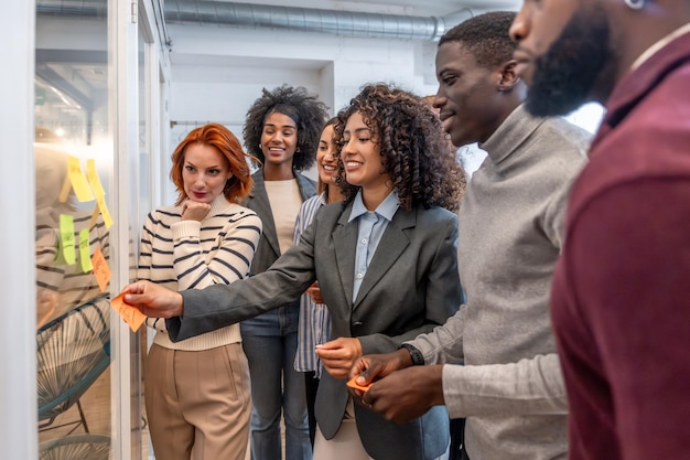 Une femme hispanique collant une note à un tableau pendant un brainstorming