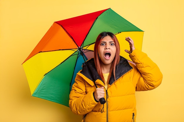 Femme hispanique criant avec les mains en l'air. concept de pluie et de parapluie