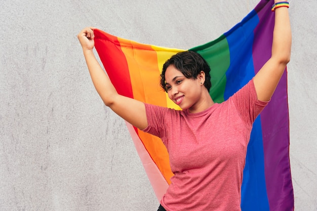 Femme hispanique debout dans la rue avec le drapeau LGTB. Notion LGBT