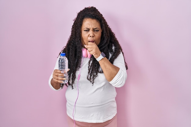 Femme hispanique de grande taille portant des vêtements de sport et des écouteurs se sentant mal et toussant comme symptôme du concept de soins de santé du rhume ou de la bronchite