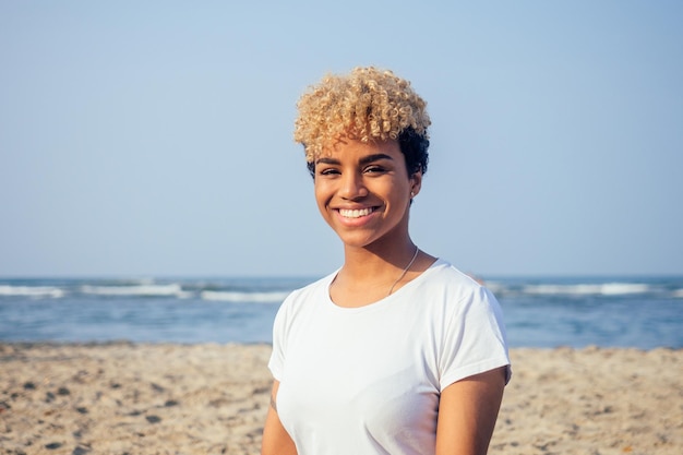 Femme hispanique latine avec une peau parfaite et des cheveux afro bouclés profitant de la plage