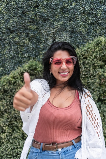 Femme hispanique en lunettes de soleil roses en plein air