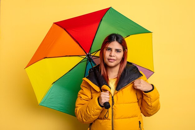 Une femme hispanique qui a l'air arrogante, réussie, positive et fière. concept de pluie et de parapluie