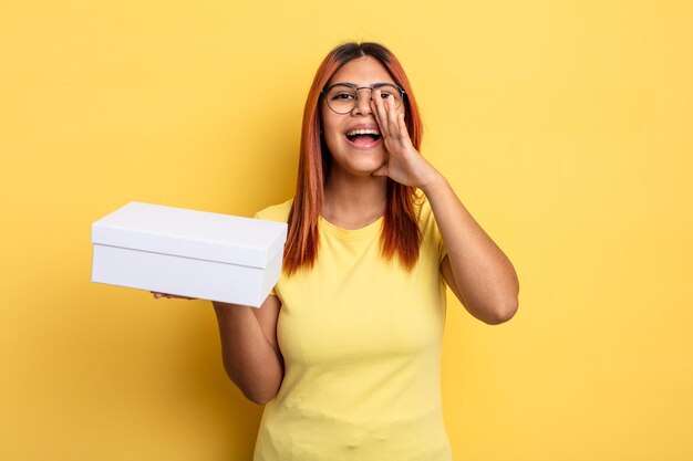 Femme hispanique se sentant heureuse, donnant un grand cri avec les mains à côté de la bouche. concept d'emballage vide