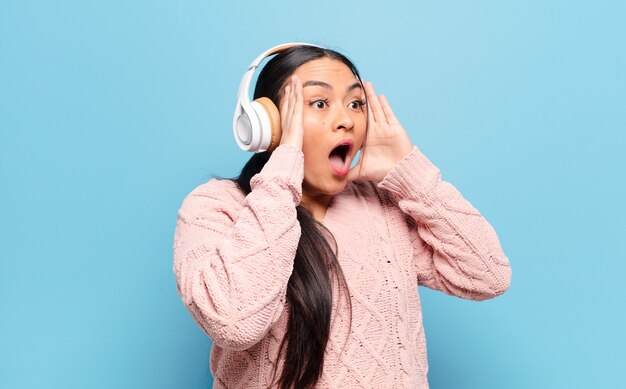 Femme hispanique se sentir heureuse, excitée et surprise, regardant sur le côté avec les deux mains sur le visage