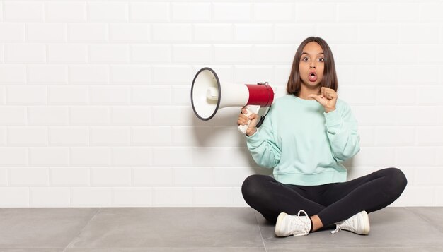 Femme hispanique semblant étonnée d'incrédulité, pointant l'objet sur le côté et disant wow, incroyable