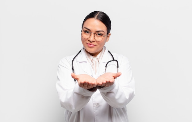 Femme hispanique souriant joyeusement avec un regard amical, confiant et positif, offrant et montrant un objet ou un concept