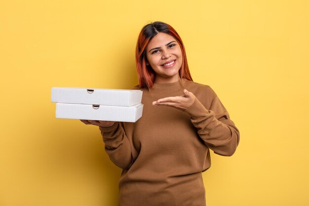 Femme hispanique souriant joyeusement, se sentant heureuse et montrant un concept. concept de pizzas à emporter