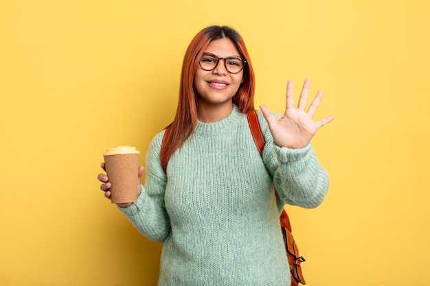 Femme hispanique souriante et sympathique, montrant le numéro cinq. étudiant avec un concept de café