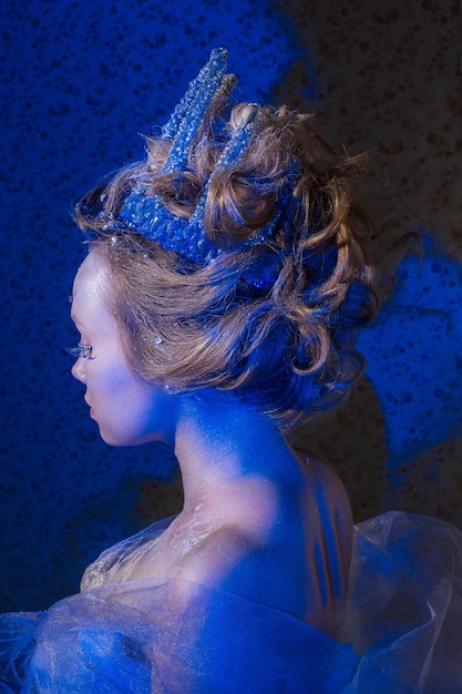 La femme d'hiver soufflant de la neige sur un fond bleu, la reine de neige.