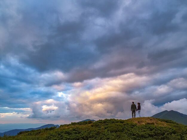 La femme et l'homme debout sur la montagne avec une vue pittoresque