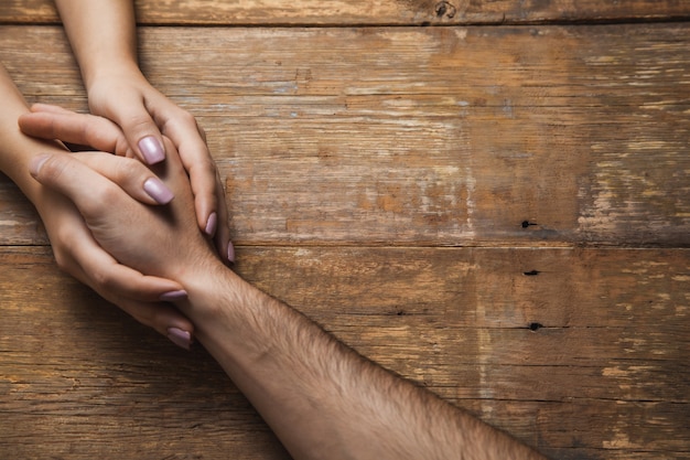 Femme et homme main dans la main sur le bureau en bois