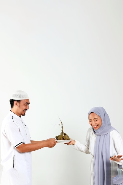 Photo femme et homme musulmans asiatiques tenant une assiette blanche avec ketupat pour la célébration de l'eid mubarak