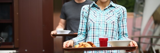 La femme et l'homme portent des plateaux de nourriture