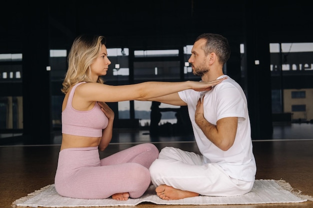 Une femme et un homme pratiquent le yoga en couple dans la salle de sport