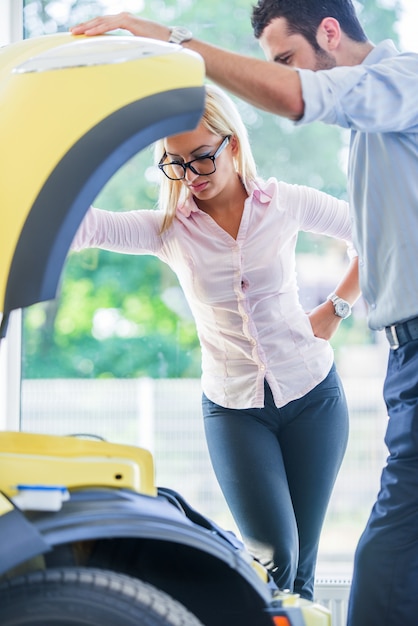 Photo femme et homme regardant sous le capot de la voiture