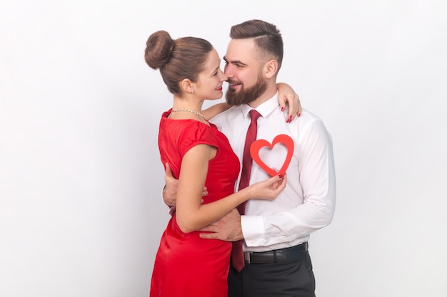 Femme et homme romantiques s'embrassant montrant un petit coeur rouge célébrant l'anniversaire