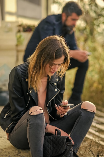 La femme et l'homme s'asseyent avec le téléphone portable