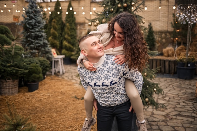 Une femme et un homme se tiennent près de l'arbre de Noël, ils sont heureux, l'humeur du nouvel an