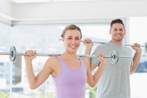 Femme et homme soulevant des haltères au studio de remise en forme