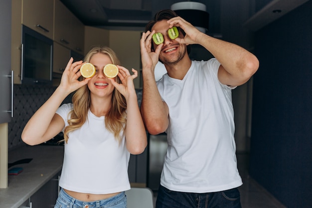 Femme et homme souriant avec une salade de fruits tropicaux, ludique couvrant ses yeux avec des fruits