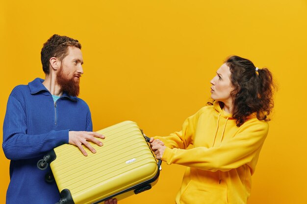 Femme et homme souriant valises à la main avec valise jaune et rouge souriant joyeusement et fond jaune tordu partant en voyage vacances en famille voyage jeunes mariés
