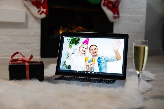 Femme Et Homme Souriants Lors D'un Appel Vidéo, Elle Est Heureuse Et Souhaite Un Joyeux Noël En Ligne, Intérieur De La Chambre Décorée En Arrière-plan