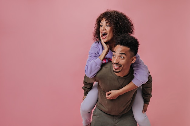 Femme et homme surpris posant sur un mur rose