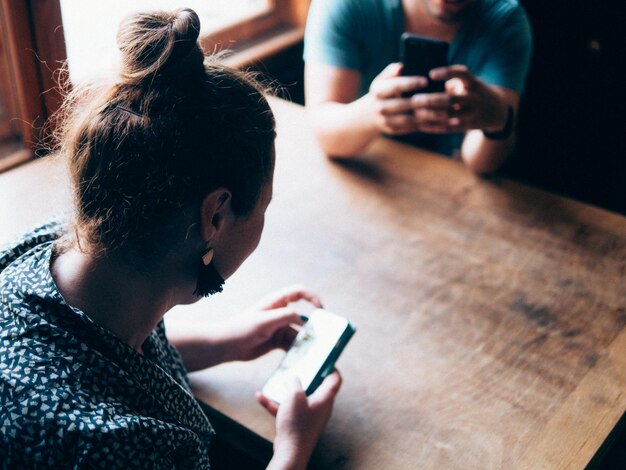 Photo une femme et un homme utilisent le téléphone à une table dans un bar.