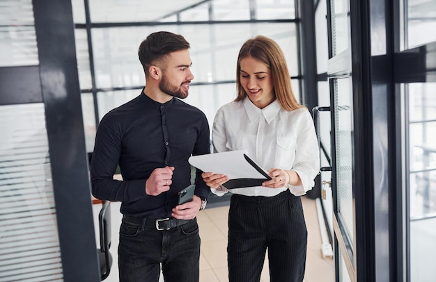 Femme et homme en vêtements formels avec des documents se parlant au bureau.