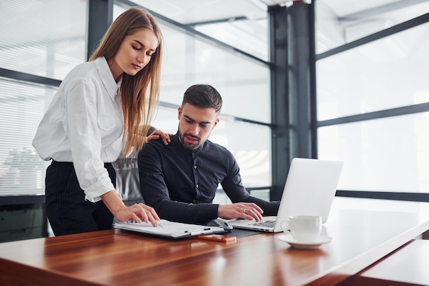 Femme et homme en vêtements formels travaillant ensemble à l'intérieur au bureau par table.