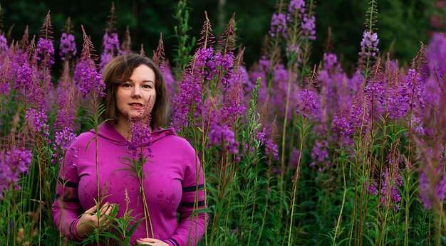 Femme en hoodie au milieu des fleurs dans le pré