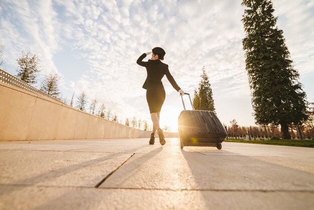 Femme en hôtesse de l'air porte une valise