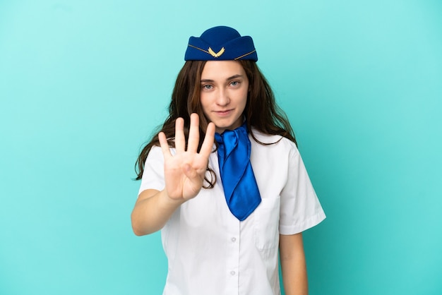 Femme hôtesse d'avion isolée sur fond bleu heureux et comptant quatre avec les doigts