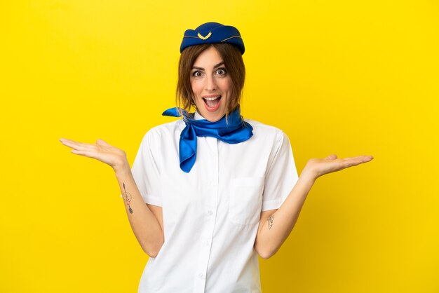 Femme hôtesse d'avion isolée sur fond jaune avec une expression faciale choquée