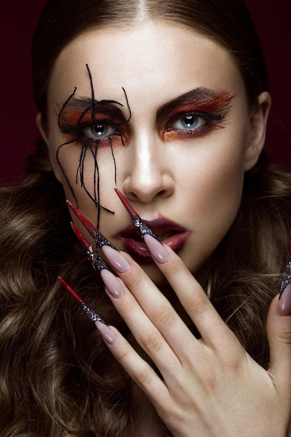 Femme à l'image de l'araignée avec maquillage d'art créatif et ongles longs Visage de beauté design manucure