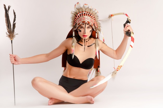 La femme à l'image des peuples autochtones d'Amérique avec un arc et une flèche pose assise sur un fond clair