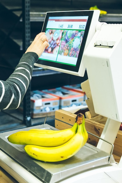 Femme imprimer un autocollant de prix pour les fruits en sélectionnant l'article nécessaire sur le poids