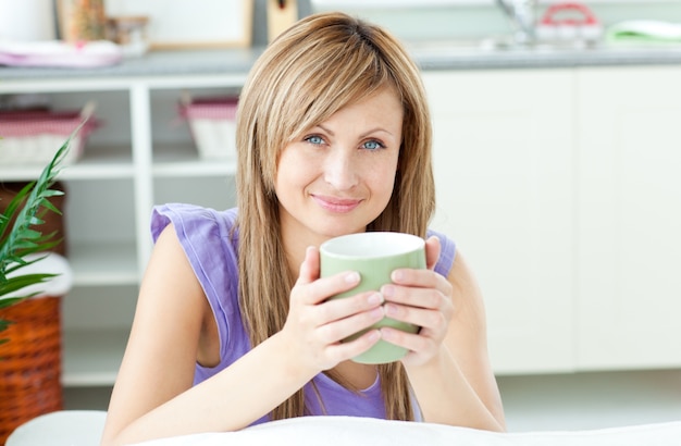 Femme incandescente tenant une tasse de café dans la cuisine