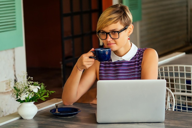 Femme indépendante indépendante avec ordinateur portable sur la plage assis dans un café d'été .business lady travail à distance surfeur surfant sur le navigateur en ligne