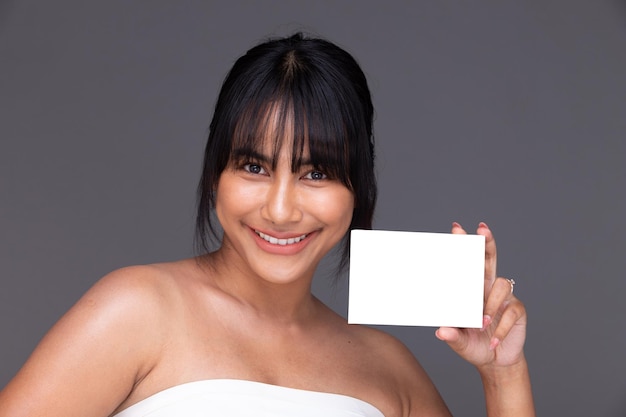 Une femme indienne asiatique montre un beau sourire des lèvres heureuses tiennent une boîte d'emballage vide vide pour la peau de traitement